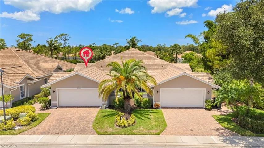 View of front facade with a tile roof, stucco siding, decorative driveway, and a garage