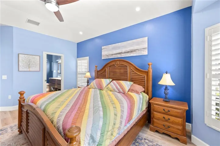 Bedroom with wood finished floors, ceiling fan, connected bathroom, and recessed lighting