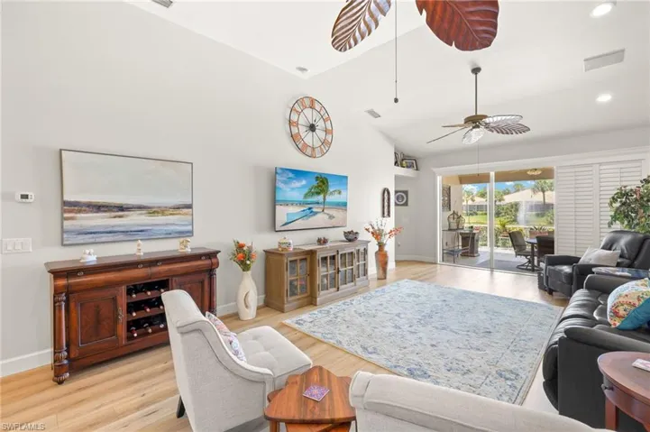 Living room featuring light wood-type flooring, a ceiling fan, recessed lighting, and high vaulted ceiling