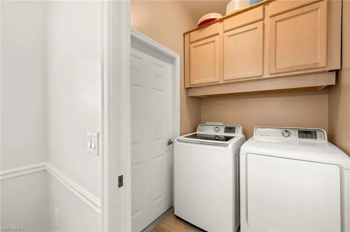 Washroom with cabinet space, independent washer and dryer, and light wood-style floors