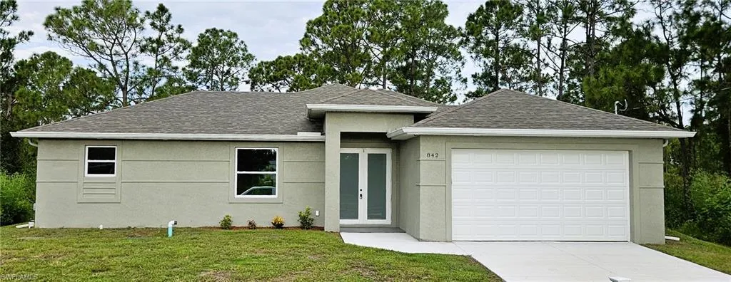 View of front of house with roof with shingles, a garage, stucco siding, a front yard, and concrete driveway