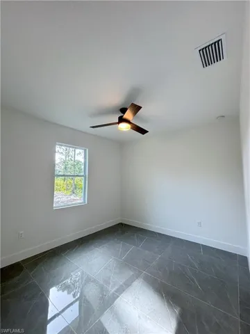 Spare room with baseboards, ceiling fan, and dark marble finish flooring
