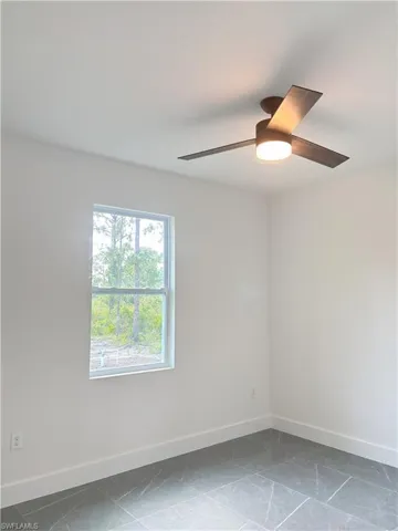 Spare room with baseboards and a ceiling fan