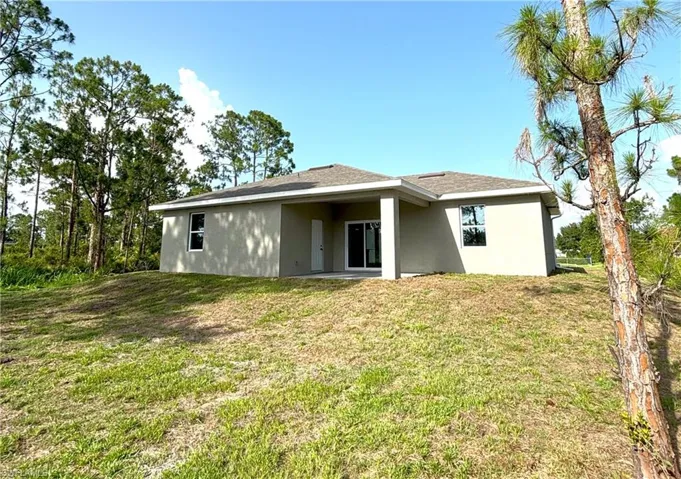 Back of property featuring stucco siding and a lawn