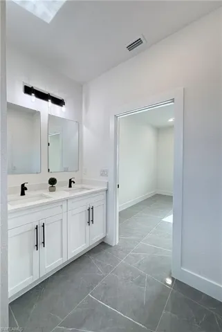 Bathroom featuring double vanity and marble finish flooring