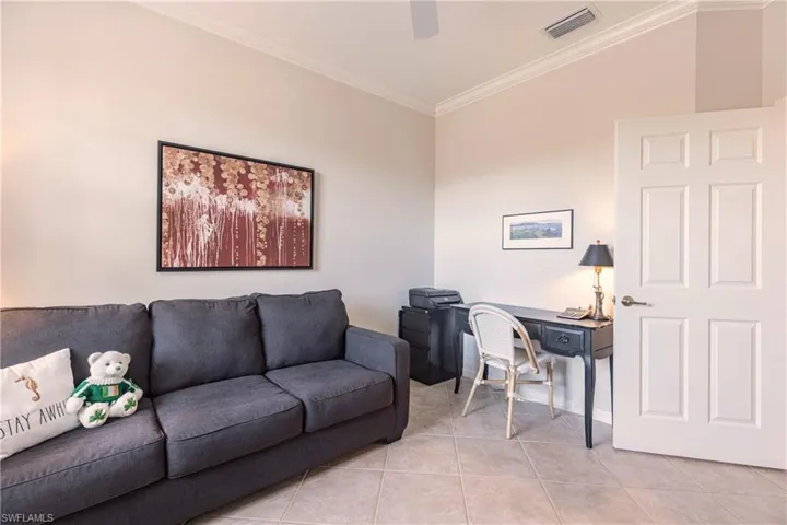 Home office with light tile patterned floors, visible vents, and crown molding and sleeper sofa