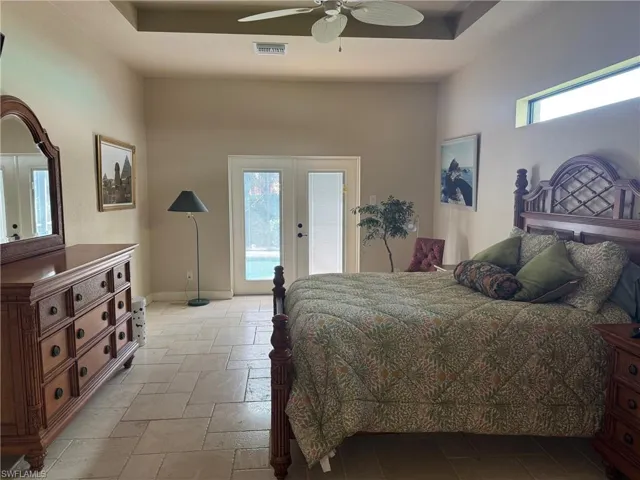 Bedroom featuring french doors, ceiling fan, a tray ceiling, and access to exterior