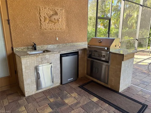 View of patio / terrace featuring area for grilling, a grill, sink, and glass enclosure