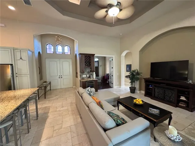 Living room with a high ceiling, a raised ceiling, and ceiling fan