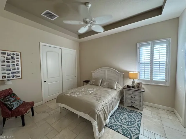 Bedroom with a tray ceiling, ceiling fan, and a closet