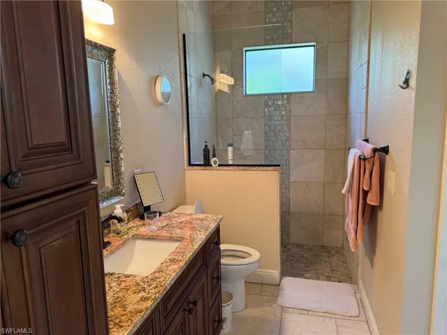 Bathroom with tiled shower, vanity, and toilet