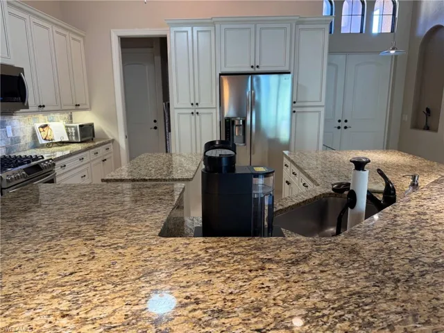 Kitchen featuring white cabinetry, light stone counters, and appliances with stainless steel finishes