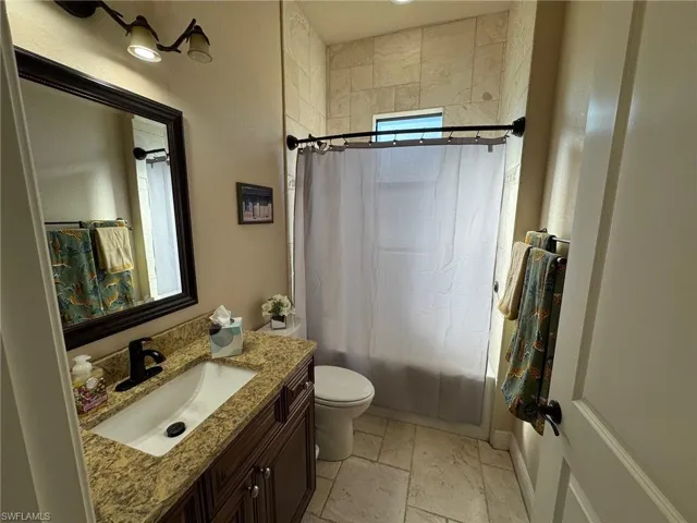 Full bathroom with shower / tub combo with curtain, vanity, and toilet