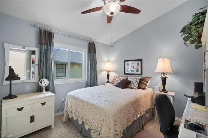 Carpeted bedroom featuring vaulted ceiling and ceiling fan