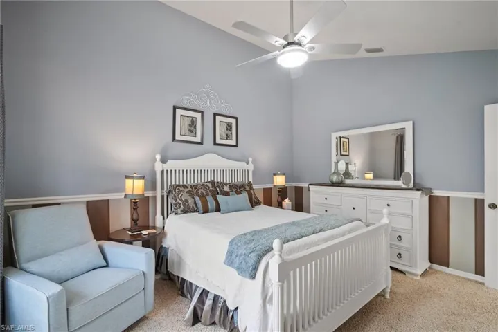 Bedroom featuring vaulted ceiling, light colored carpet, and ceiling fan