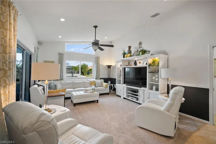 Living room featuring high vaulted ceiling, light colored carpet, and ceiling fan