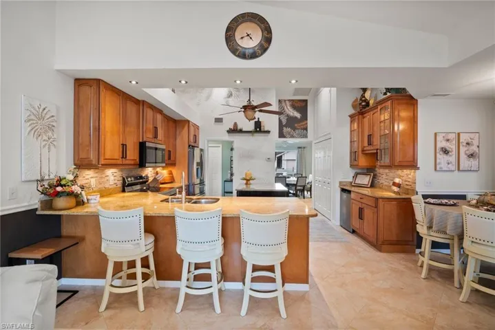 Kitchen featuring high vaulted ceiling, kitchen peninsula, a kitchen bar, and stainless steel appliances