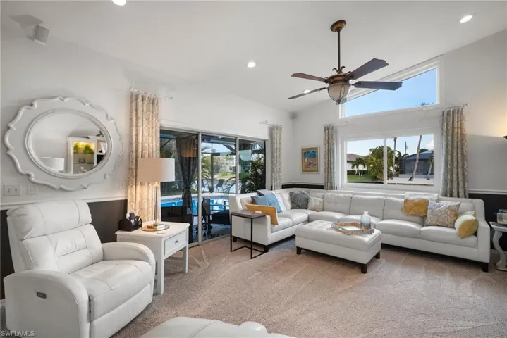 Carpeted living room featuring ceiling fan, a healthy amount of sunlight, and vaulted ceiling
