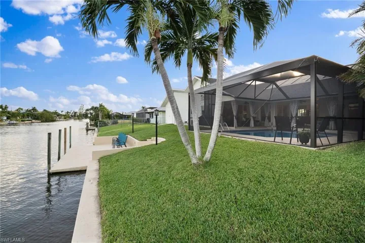 View of yard with a dock, glass enclosure, and a water view