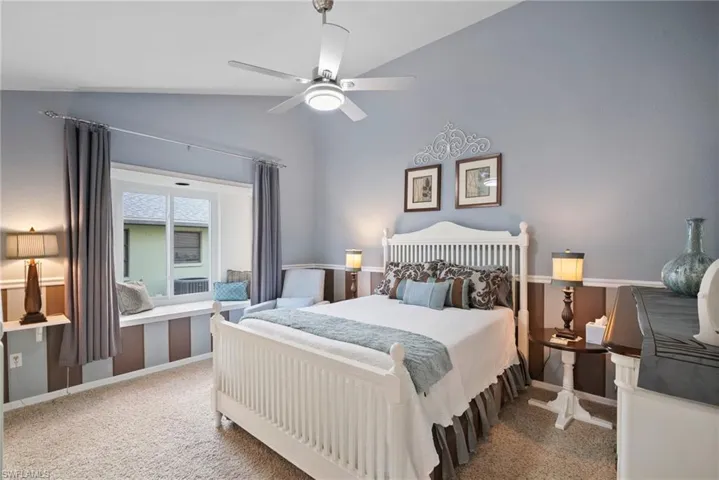 Bedroom with carpet floors, ceiling fan, and vaulted ceiling