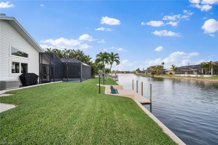 Dock area with a water view, glass enclosure, and a lawn
