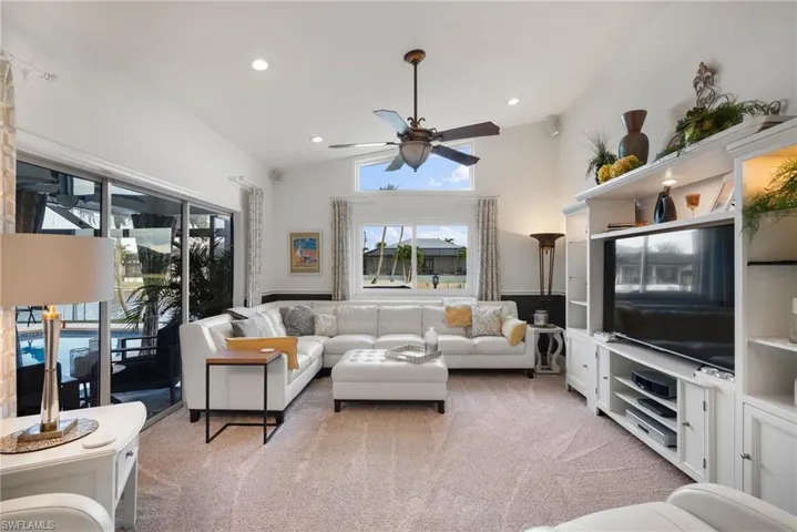 Living room with carpet flooring, ceiling fan, and vaulted ceiling