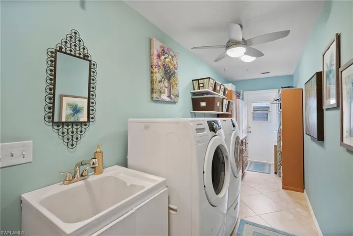 Laundry room featuring washer and clothes dryer, sink, light tile patterned floors, and ceiling fan