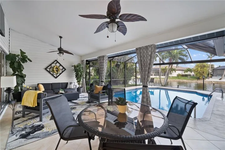 View of patio featuring glass enclosure, outdoor lounge area, a water view, and ceiling fan
