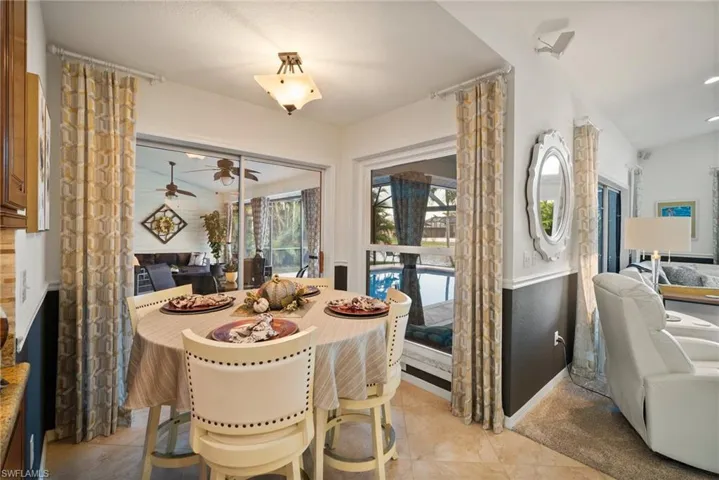 Dining area with ceiling fan, light tile patterned floors, and lofted ceiling