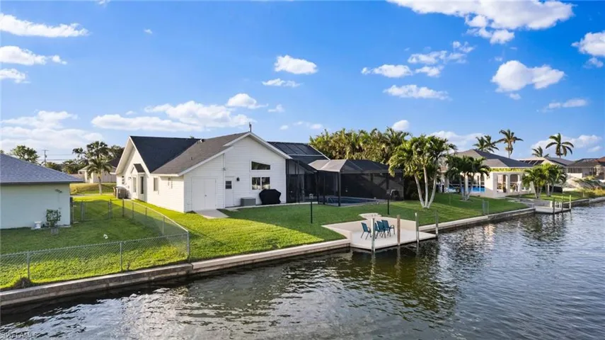 View of dock with a water view, glass enclosure, and a yard