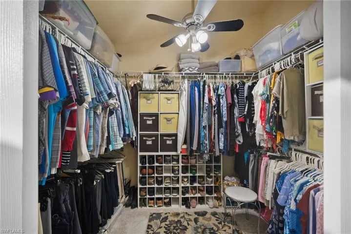 Walk in closet with carpet flooring, lofted ceiling, and ceiling fan