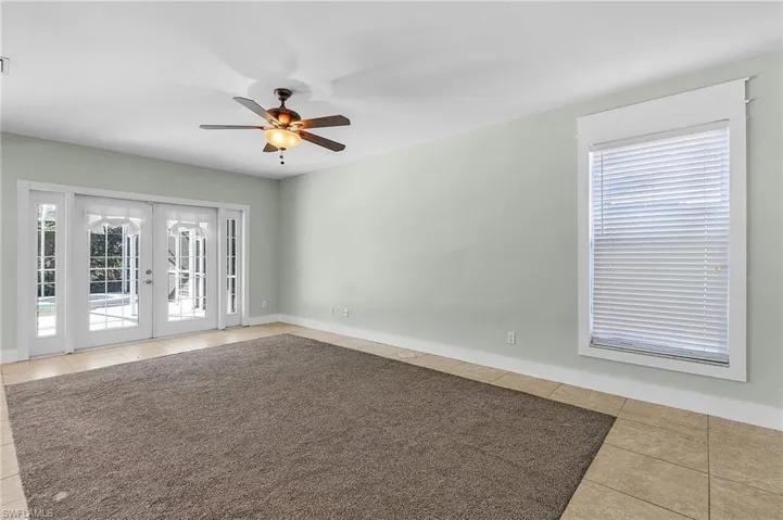 Spare room featuring french doors, tile patterned floors, ceiling fan, and a healthy amount of sunlight