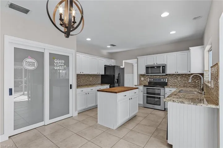 Kitchen featuring wood counters, sink, white cabinetry, and stainless steel appliances