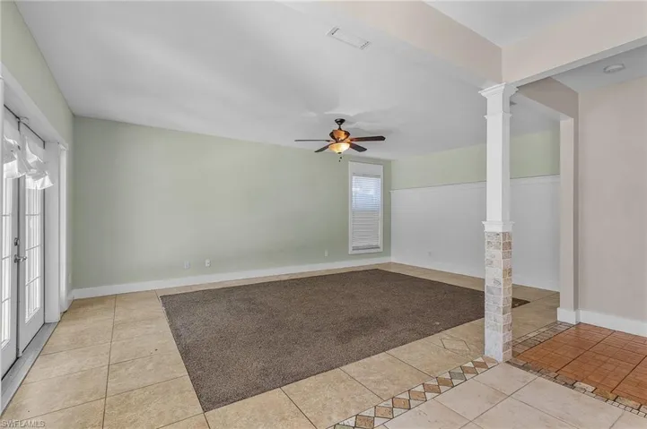 Unfurnished room with ceiling fan, light tile patterned floors, french doors, and decorative columns