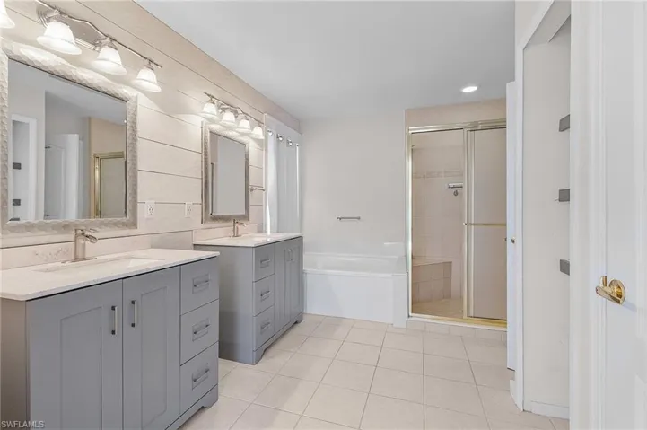 Bathroom with tile patterned floors, vanity, and plus walk in shower