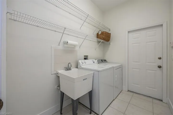 Laundry room featuring washer and dryer, utility sink, ample shelving and tile floors