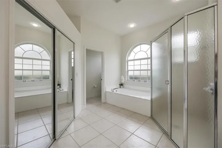 walk in closet inside bathroom with tub, shower and doorway to water closet
