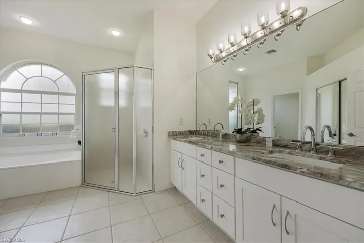Double sink vanity, shower and separate tub with arch window