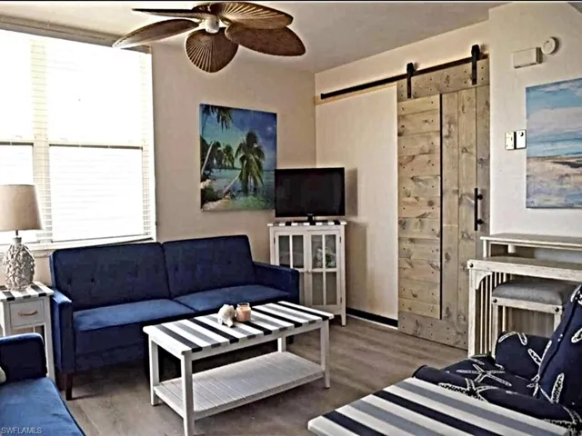 Living room with a barn door, a ceiling fan, and wood finished floors
