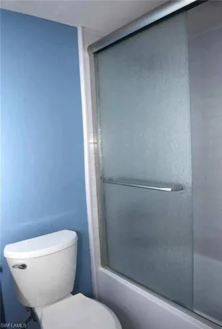 Bathroom featuring enclosed tub / shower combo and toilet