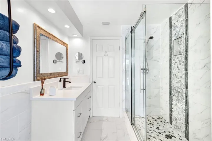 Master shower with decorate stone accents in all new shower with rimless glass surround.
