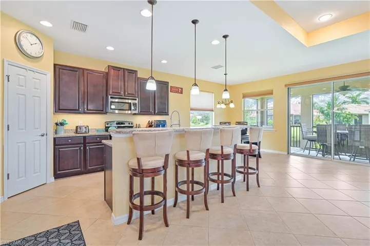 Kitchen featuring appliances with stainless steel finishes, pendant lighting, an island with sink, a kitchen bar, and light tile patterned floors