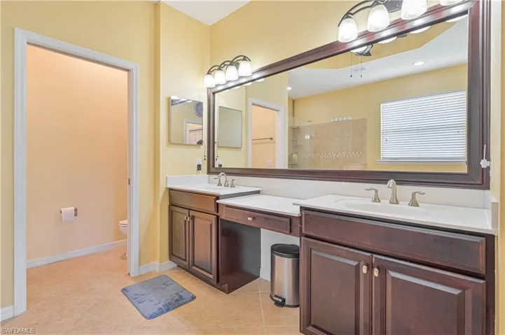 Bathroom with tile patterned flooring, vanity, a tile shower, and toilet