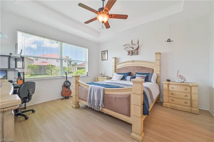Bedroom with hardwood / wood-style flooring, a raised ceiling, and ceiling fan