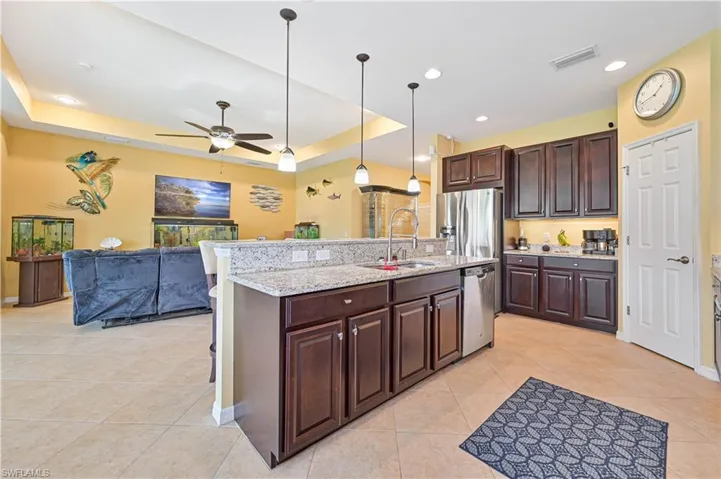 Kitchen with stainless steel appliances, a tray ceiling, sink, and hanging light fixtures