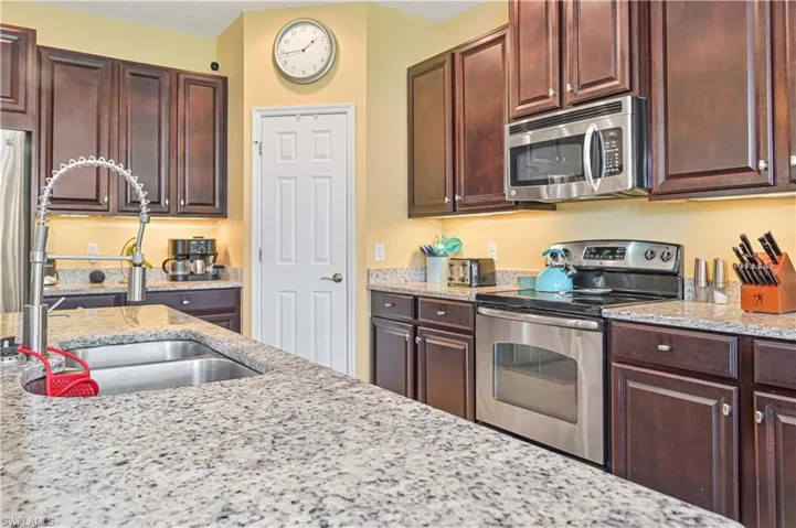 Kitchen with stainless steel appliances, light stone countertops, and sink