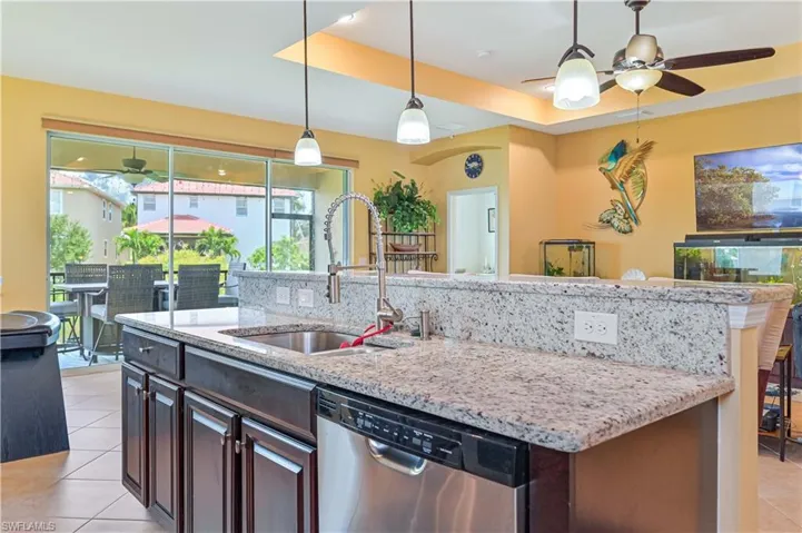 Kitchen featuring sink, a kitchen island with sink, dark brown cabinetry, a tray ceiling, and stainless steel dishwasher