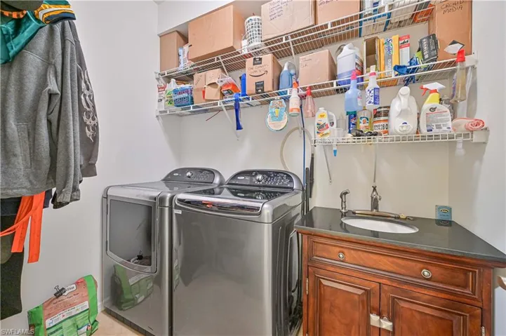 Clothes washing area featuring sink, washer and clothes dryer, and cabinets