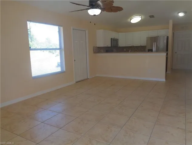 Family room and kitchen with white cabinets, stainless steel appliances, and light tile patterned flooring