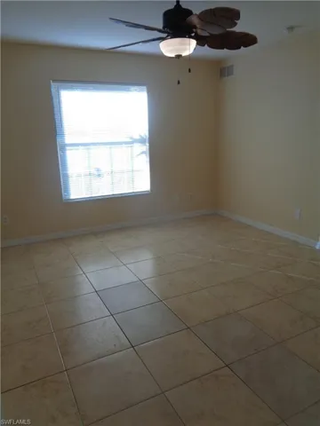 Master bedroom with light tile patterned floors and ceiling fan